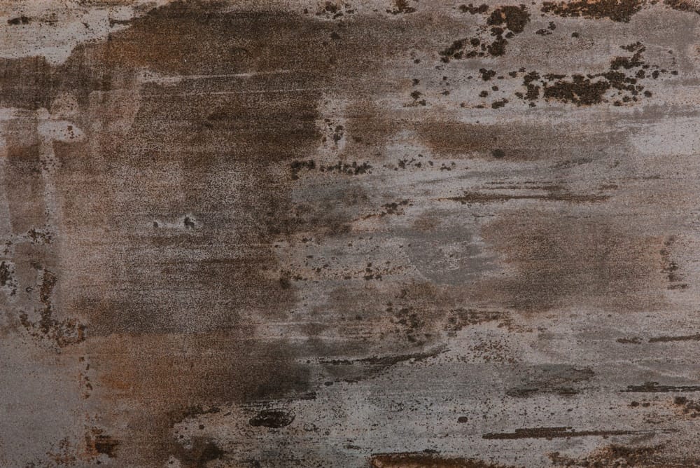 Rusty, weathered metal surface in gray and brown with stains and texture